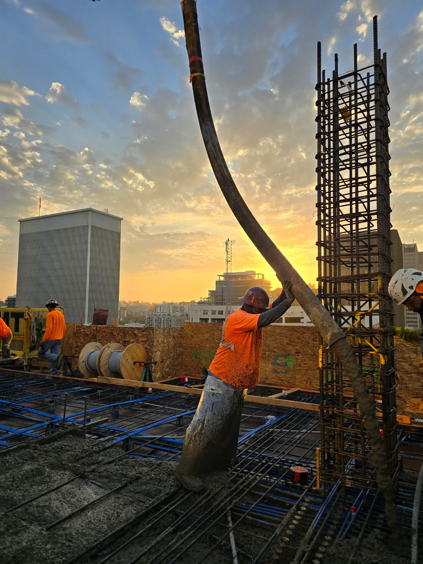 Smokes Concrete crew guiding a concrete pump against the San Diego skyline at sunset